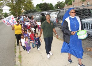 Led by Sister Maurice Okoroji, right, Director of Harmony House Early Learning Center, the students and staff waved flags, held banners and marched on the sidewalk. Okoroji said it’s important to teach the younger generations who weren’t born then about both the lives lost and the heroism displayed on that day.