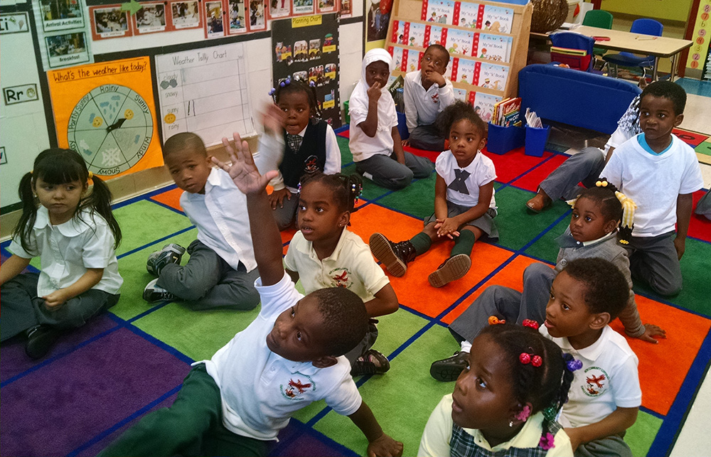 Gregory, seated in front raising his hand, has made strides in his personal and educational development at NCC Community Hills Early Learning Center.
