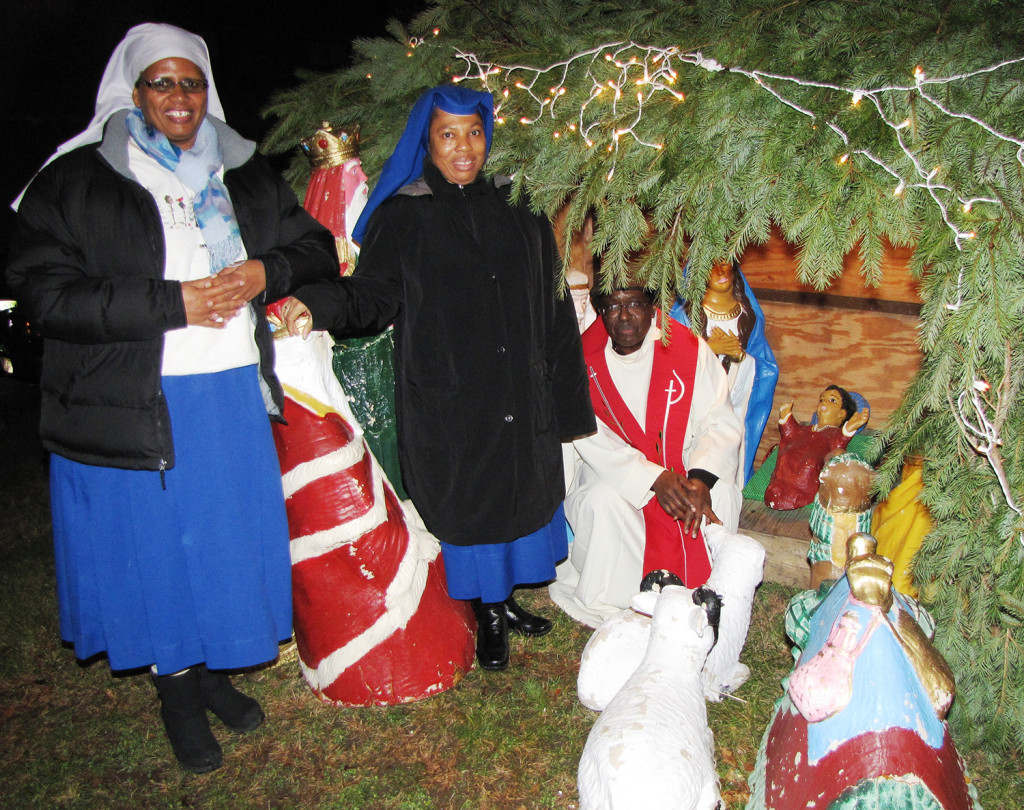 From left: Sister Theresia Hhayuma, Sister Mary Prisca and Father Beatus Kitururu gathered with residents of NCC Manor Senior for the crib blessing at the nativity scene displayed in front of 545 Orange St. in Newark.