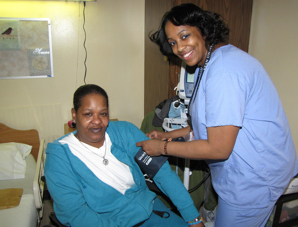 Teresa Watkins, seated left, a resident of New Community’s Extended Care Facility, gets her blood pressure checked by Licensed Practical Nurse Maria Cruz. 
