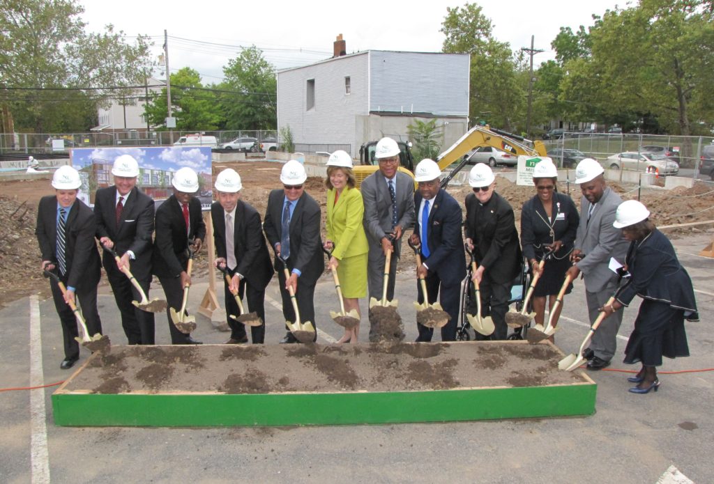 Officials and community leaders gathered at New Community Corporation in Newark and broke ground on A Better Life on September 28, 2016. From left: George Serio, director of the Essex County Division of Housing and Community Development; James Robertson, chief of Legal and Regulatory Affairs, New Jersey Housing and Mortgage Finance Agency; Baye Adofo-Wilson, deputy mayor for Economic and Housing Development, City of Newark; Julio Colon, director of the Department of Housing Assistance, City of Newark; Richard Rohrman, CEO of New Community; Rosemarie Rosati, COO of Rutgers University Behavioral Health Care; Richard Roberts, managing director of Acquisitions at Red Stone Equity Partners; Mayor Ras Baraka, City of Newark; Monsignor William J. Linder, founder and board chair of New Community; Stephanie Welch, program assistant at University Hospital Public Affairs; Thaddaeus L. Diggs, director of Government Relations, Office of General Counsel at University Hospital; Mildred Crump, council president, City of Newark.