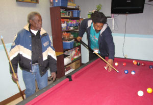 Maurice Okereke, right, activity assistant at New Community Extended Care Facility, shoots a game of pool with resident Lee L. Burgman, left.