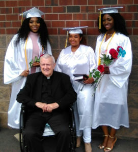 Monsignor William J. Linder poses with scholarship recipients Chikama Onwunaka, Sibonai Ruthie Geberyesus and Maryana Okoye (left to right) who received their diplomas from Saint Vincent Academy June 4. Photo courtesy of Madge Wilson.