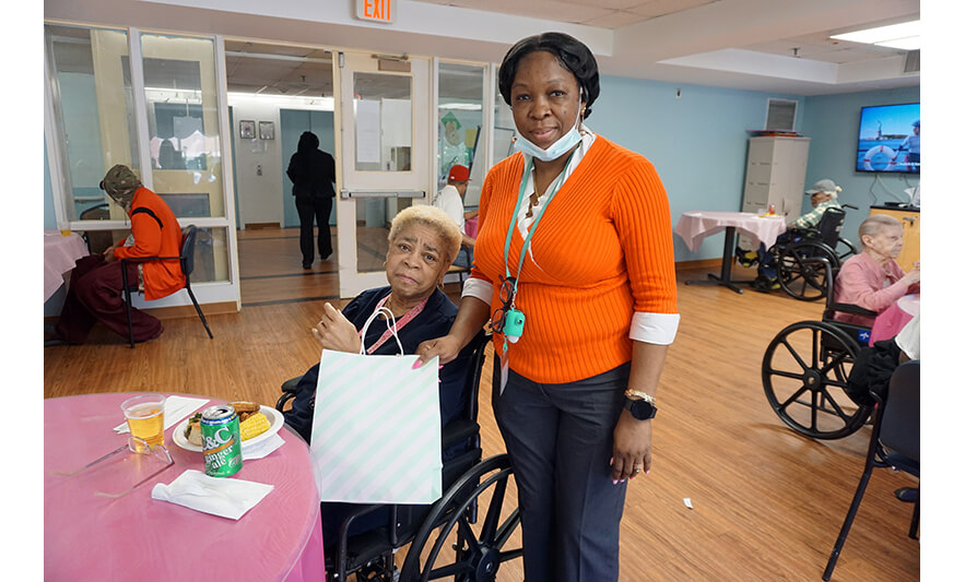 Extended Care Adopt-A-Resident Day 5-17-2023 Yonette Semple giving woman striped bag for web